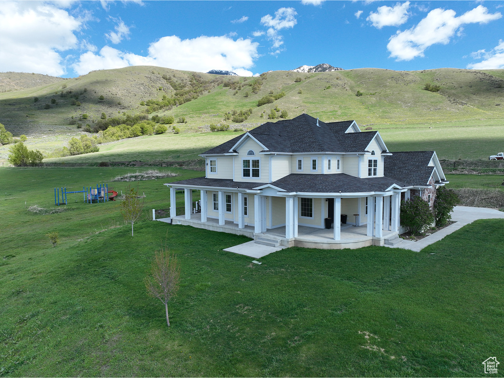 Back of house featuring a porch, a lawn, and a mountain view