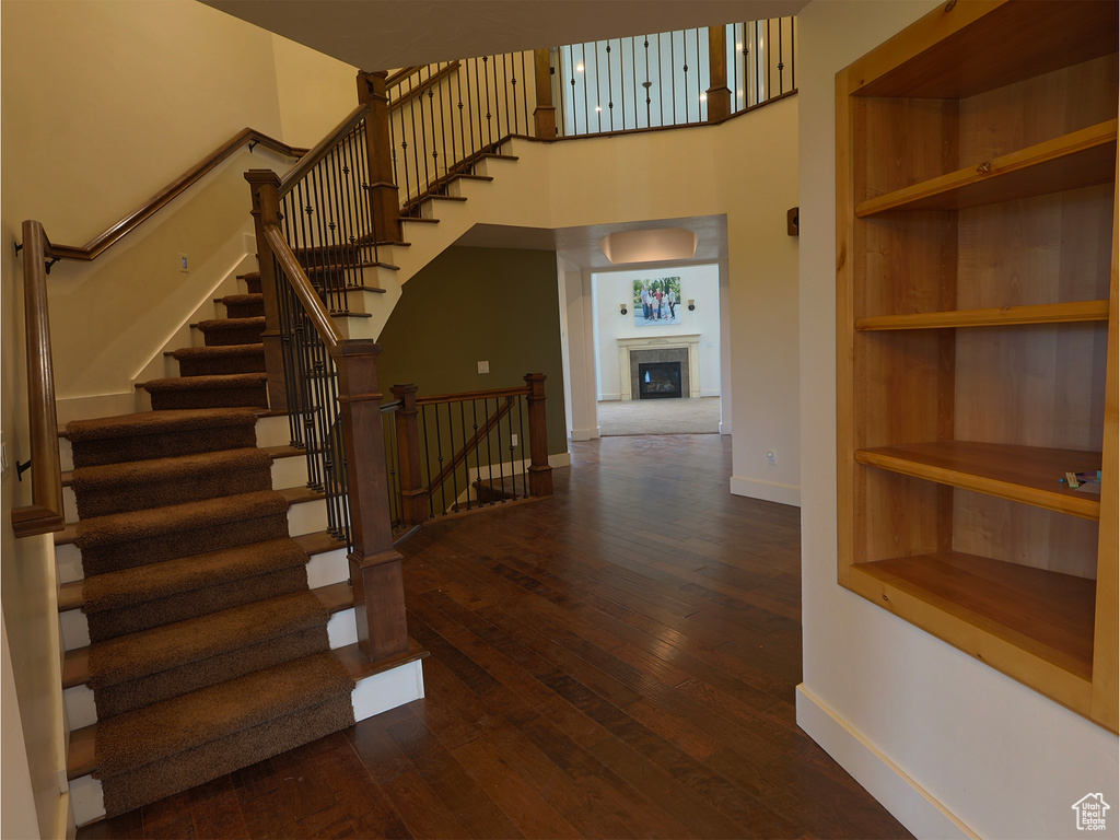 Staircase featuring baseboards, a high ceiling, hardwood / wood-style floors, and a fireplace