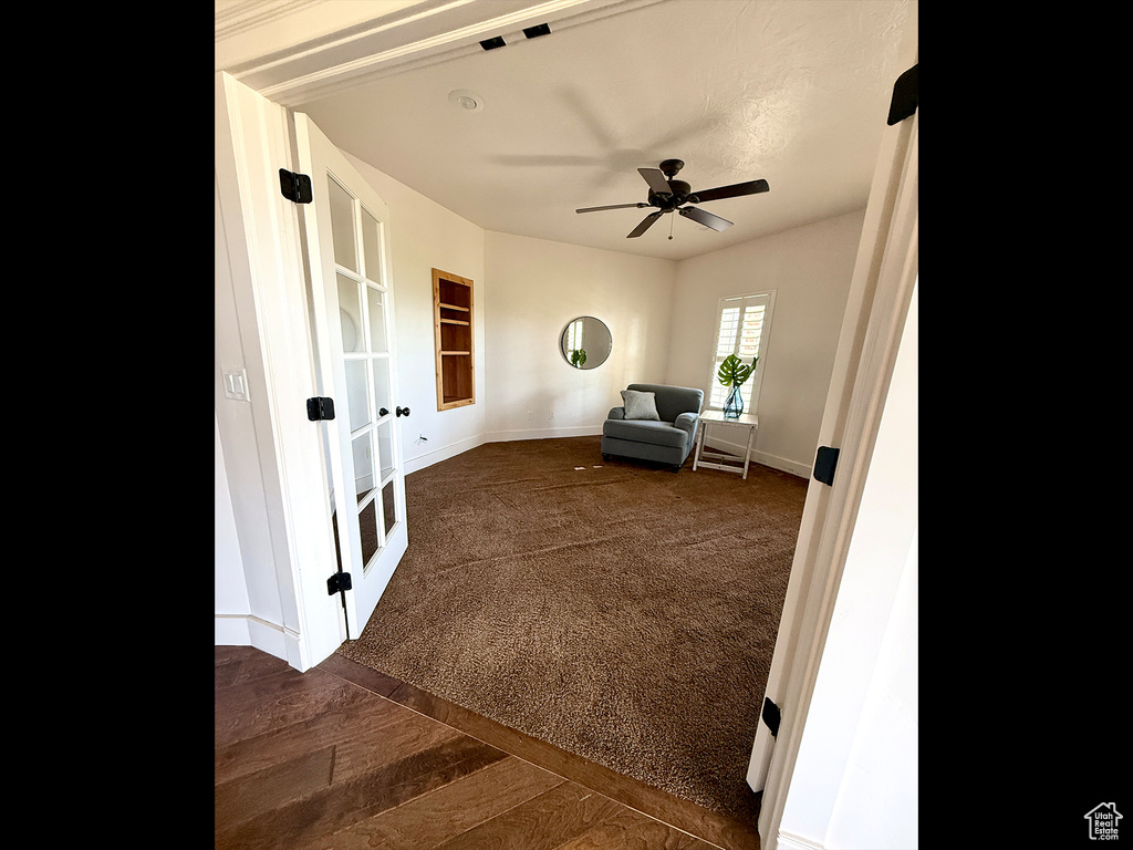 Sitting room featuring french doors, ceiling fan, and dark carpet