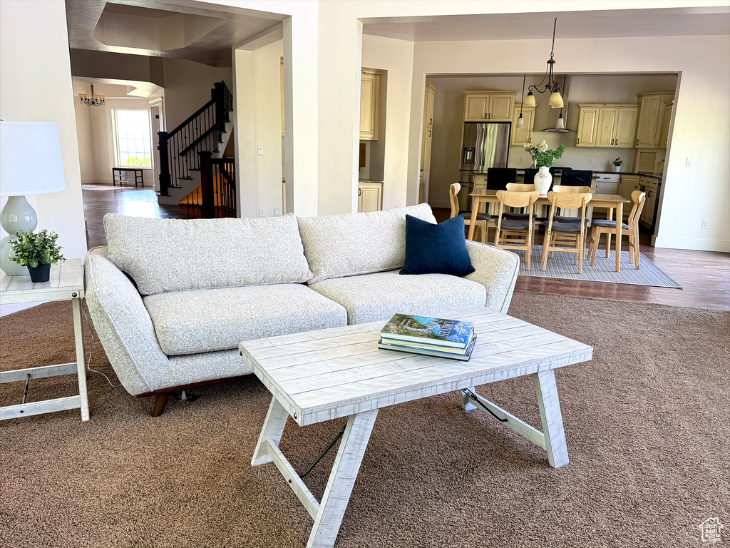 Carpeted living area with stairs and a chandelier