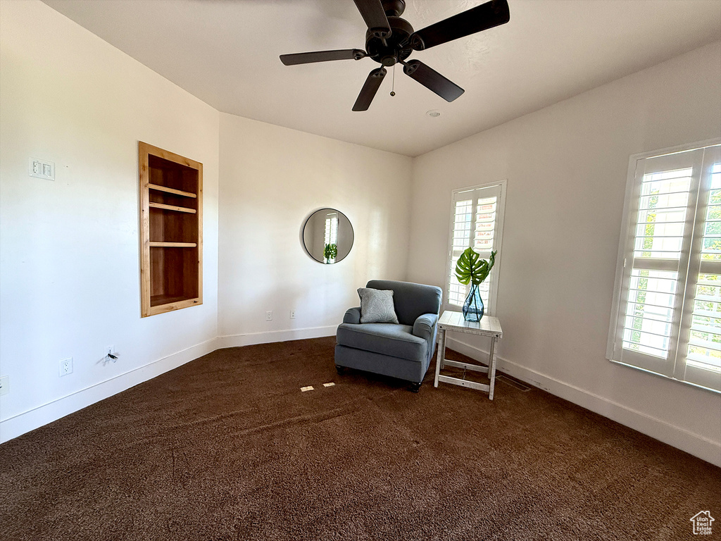 Sitting room with plenty of natural light, dark colored carpet, and ceiling fan