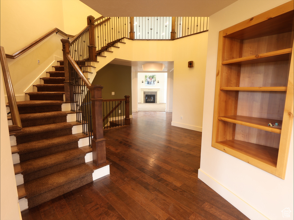 Stairway featuring baseboards, wood-type flooring, and a high ceiling