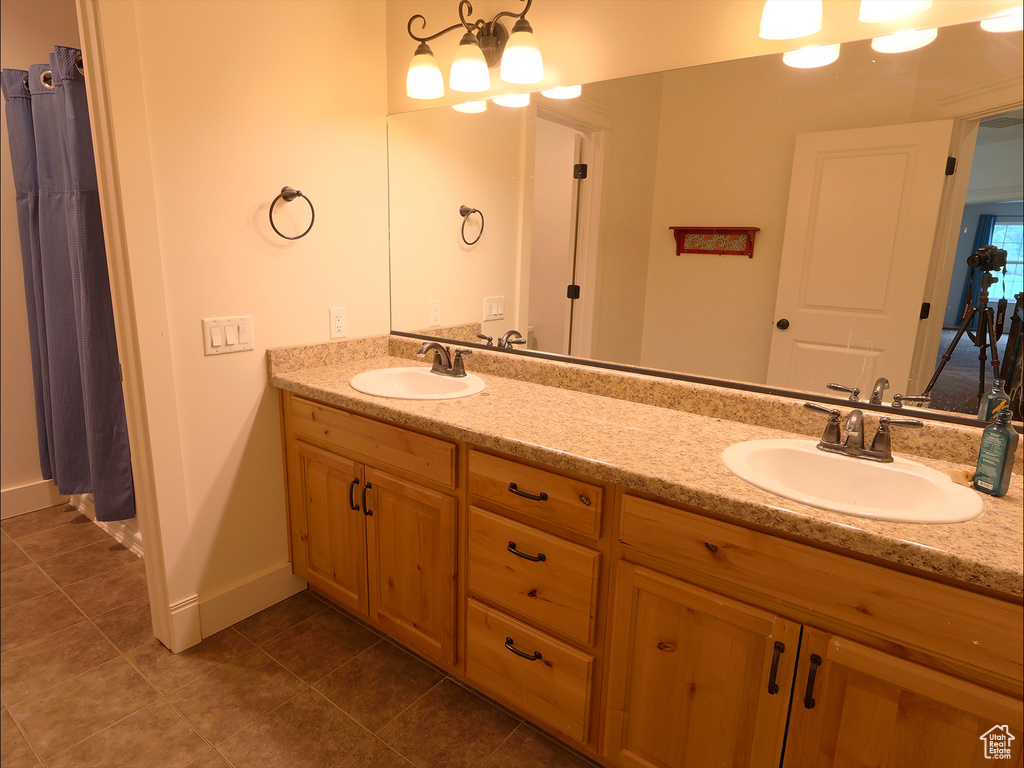 Bathroom featuring tile patterned flooring, double vanity, baseboards, and a chandelier