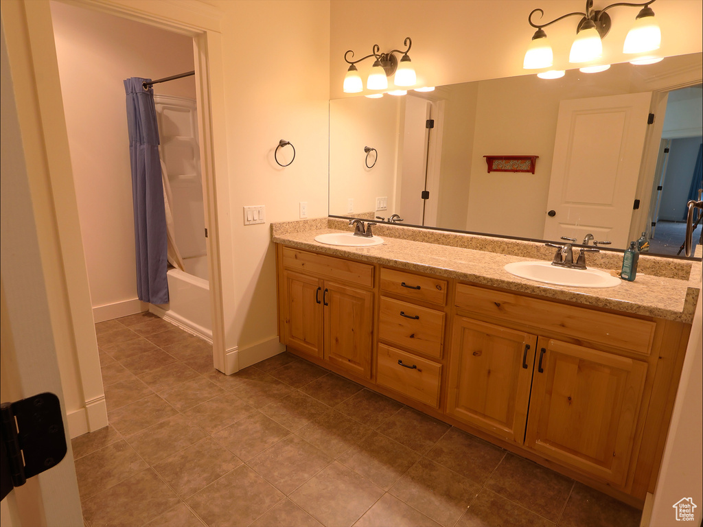 Bathroom with double vanity, tile patterned flooring, shower / tub combo, and baseboards