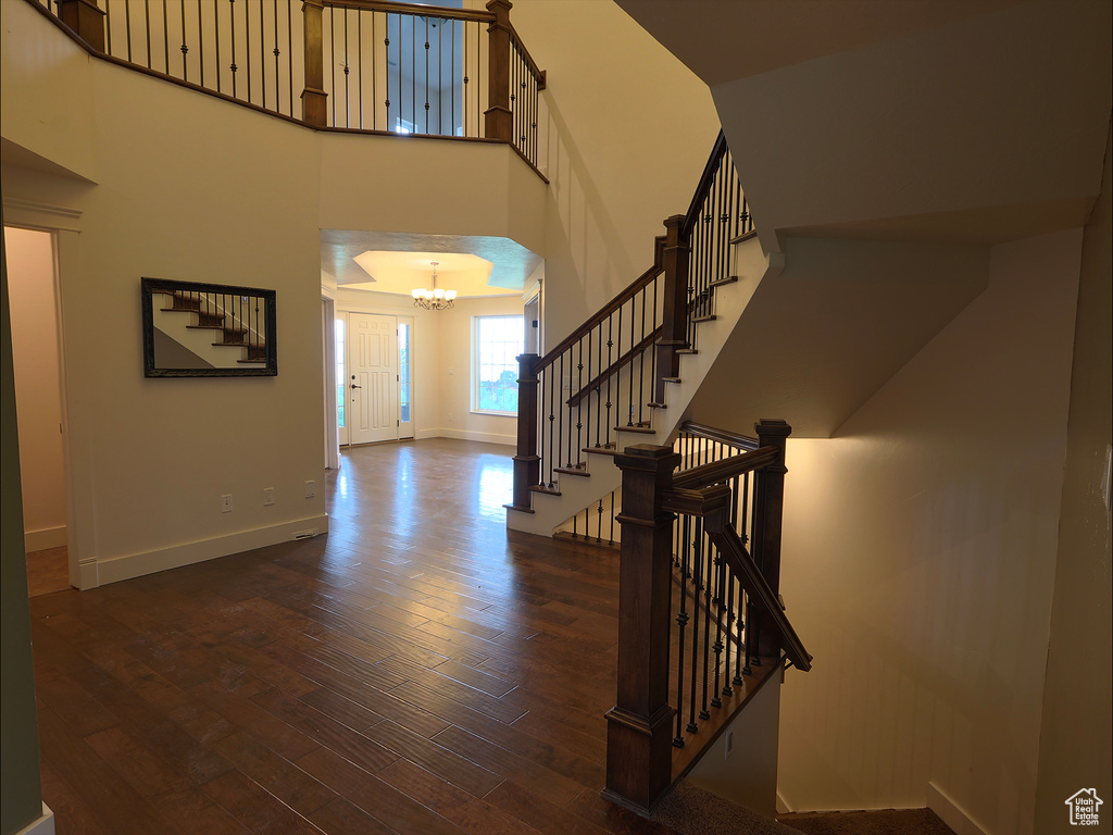 Entrance foyer featuring a chandelier, wood finished floors, stairway, baseboards, and a towering ceiling