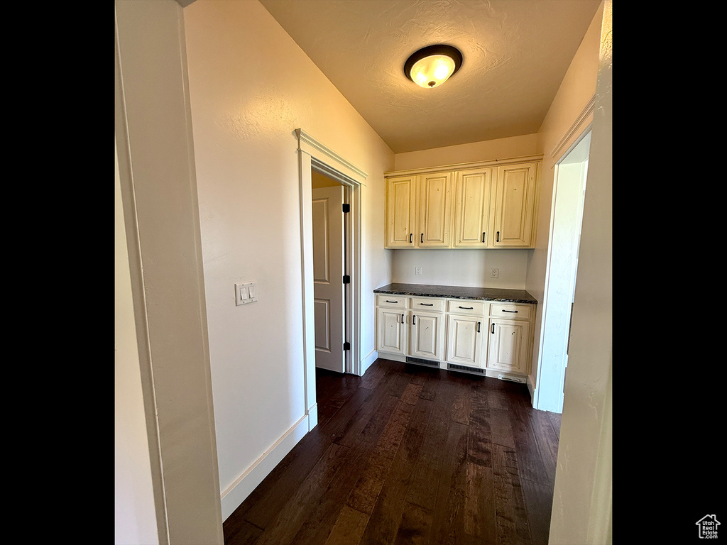 Corridor featuring dark wood finished floors and baseboards