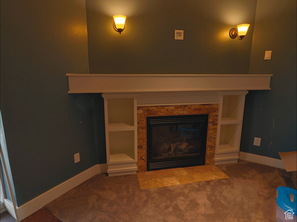 Detailed view of a fireplace with flush hearth, carpet, and baseboards