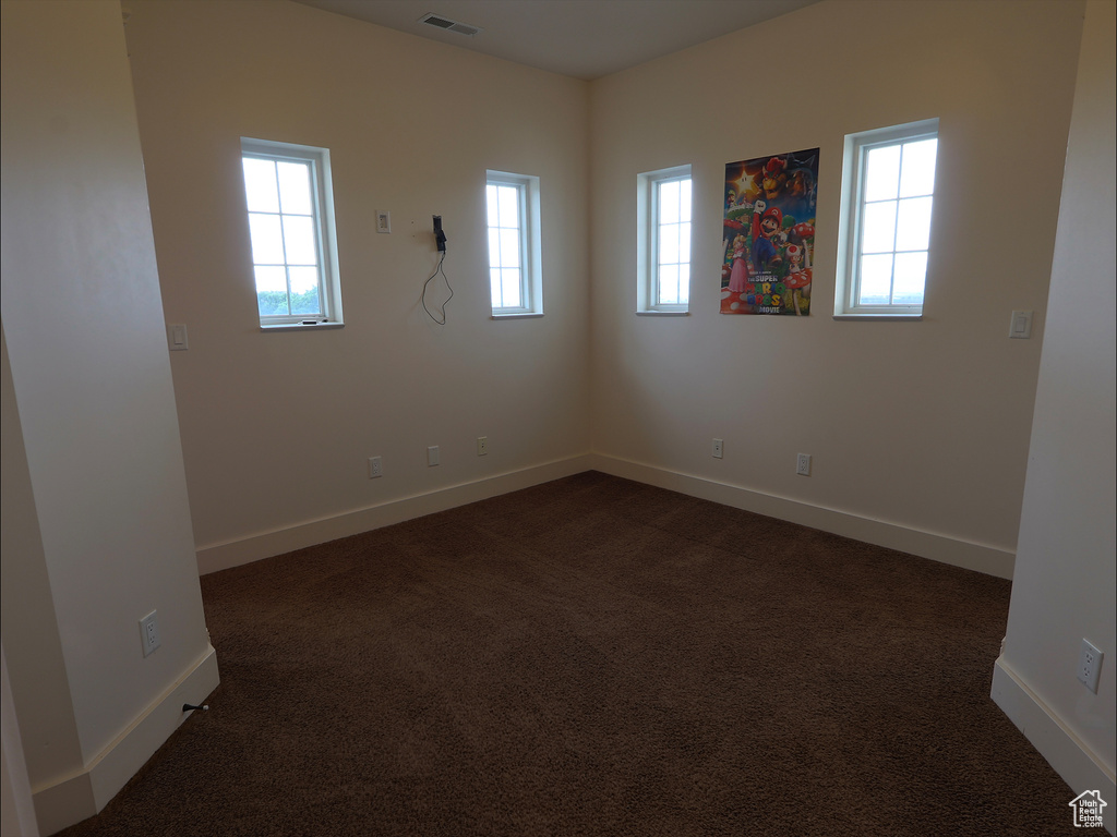 Spare room featuring baseboards and dark carpet