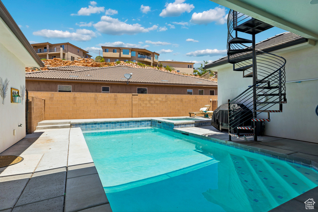 View of pool with a fenced backyard, grilling area, a pool with connected hot tub, and a patio