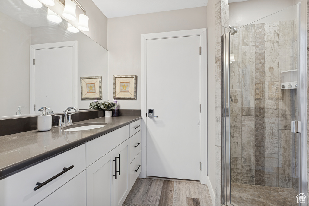 Full bath featuring vanity, a stall shower, and wood finished floors