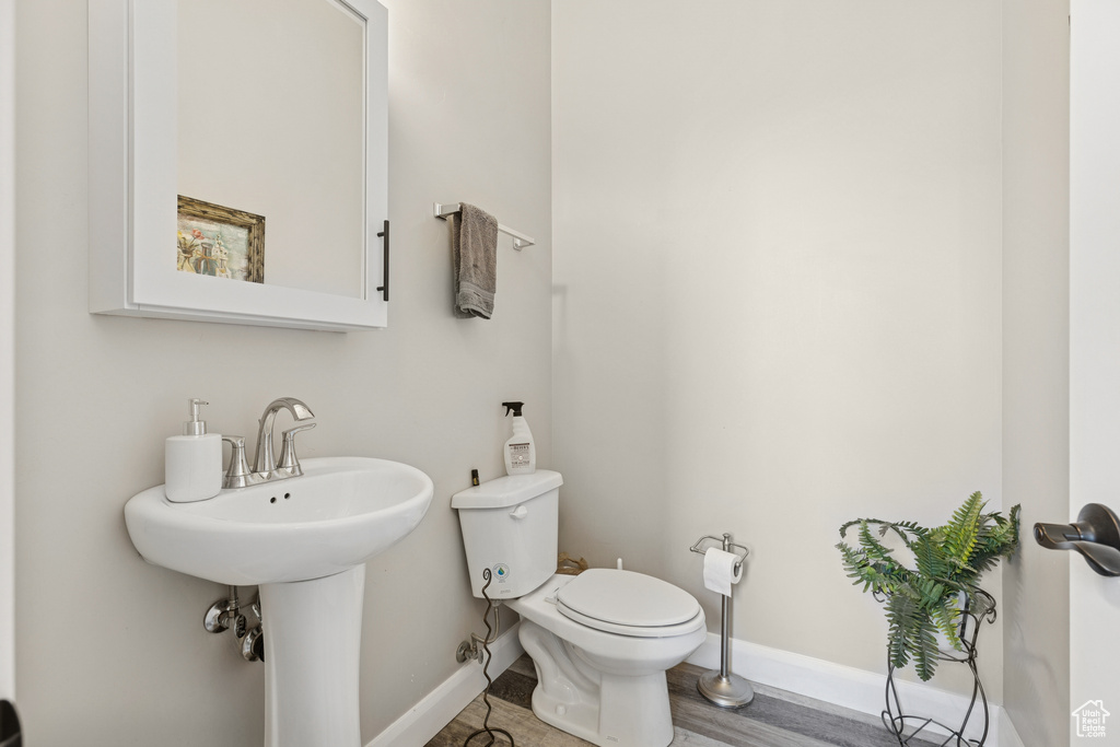 Half bath featuring baseboards, toilet, and a sink