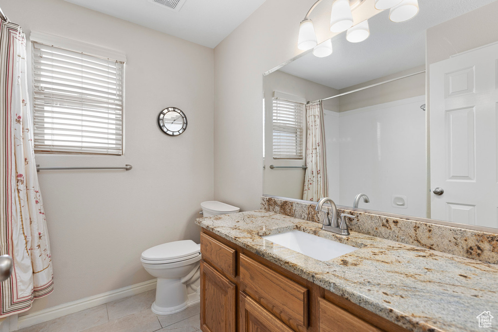 Bathroom featuring vanity, toilet, tile patterned flooring, baseboards, and a shower with shower curtain