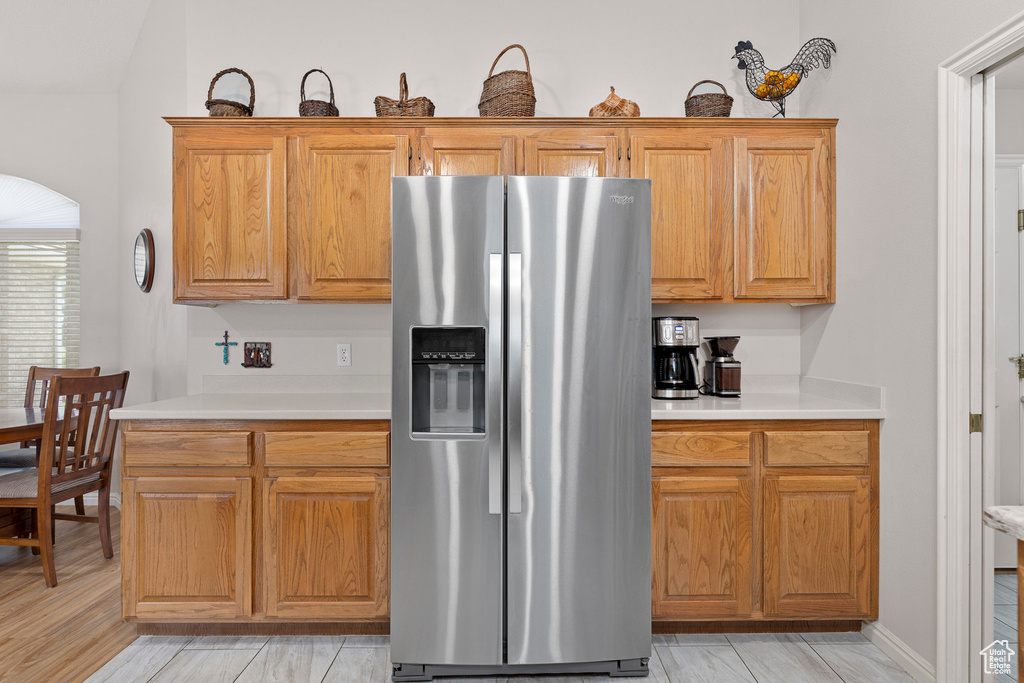 Kitchen featuring stainless steel fridge, light countertops, and arched walkways