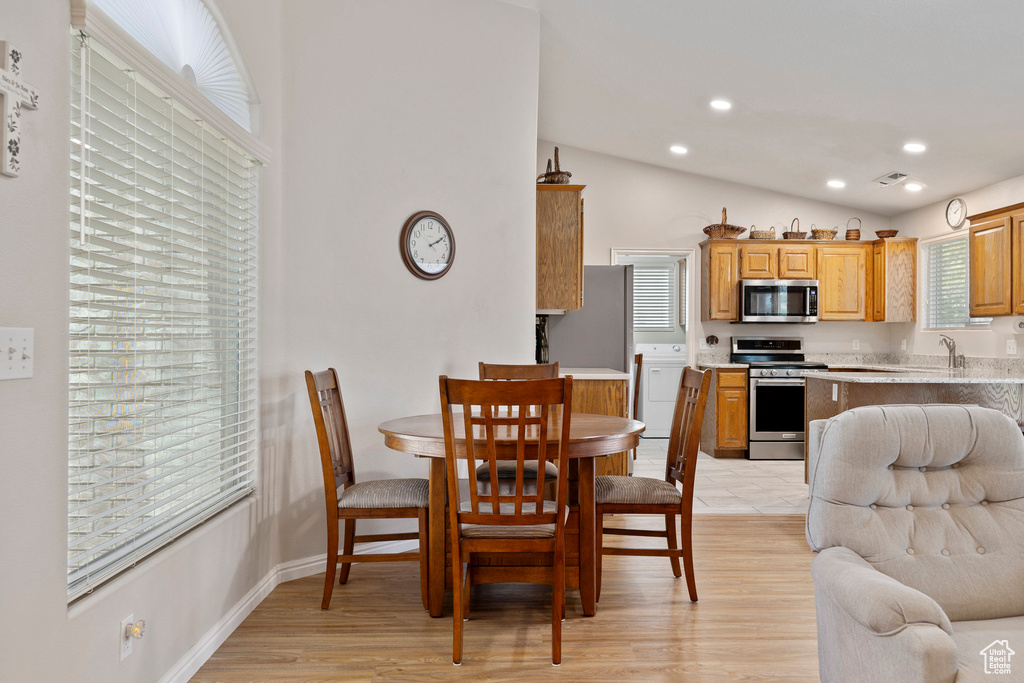 Dining space with light wood finished floors, lofted ceiling, recessed lighting, and washer / dryer