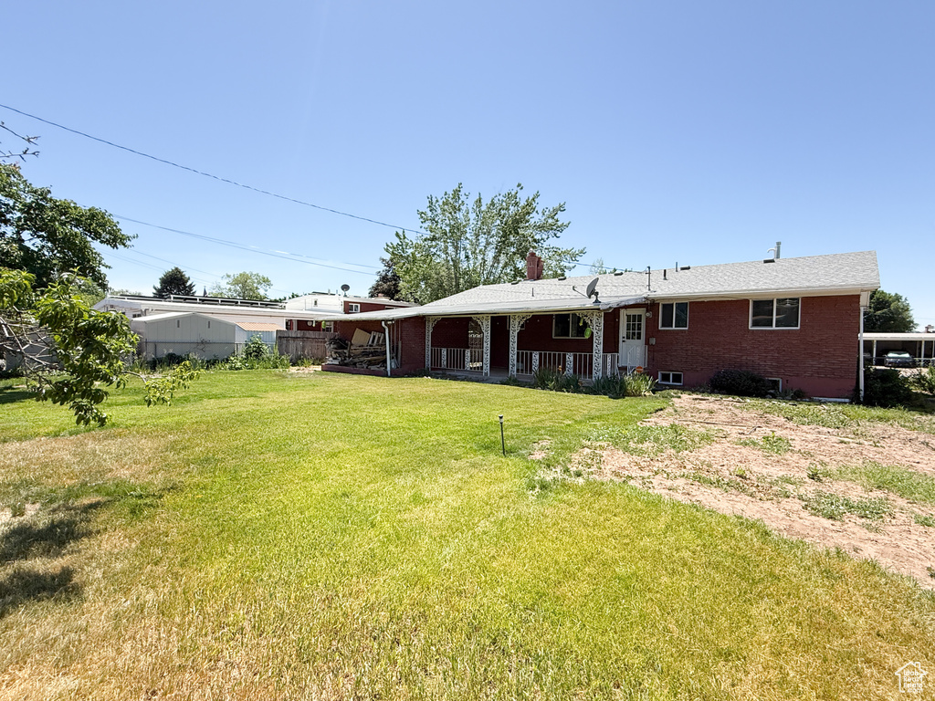 Rear view of property featuring a lawn, brick siding, and a chimney