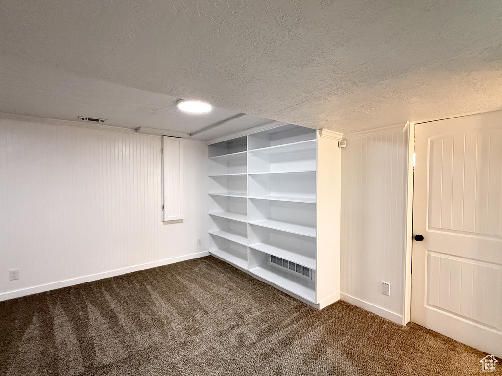 Finished basement with carpet, baseboards, and a textured ceiling