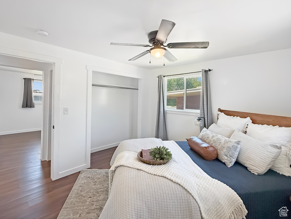 Bedroom with a closet, dark wood-style floors, ceiling fan, and baseboards