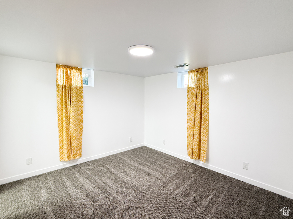 Spare room featuring baseboards and dark carpet