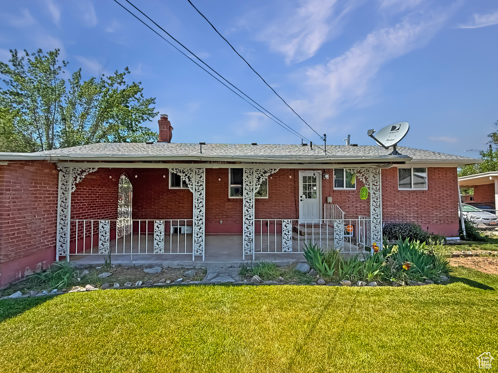 View of front of property featuring a front lawn, brick siding, and a chimney