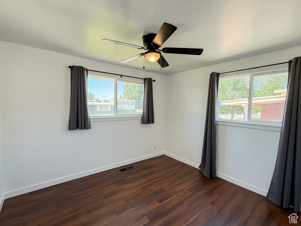 Unfurnished room with dark wood-type flooring, baseboards, and ceiling fan