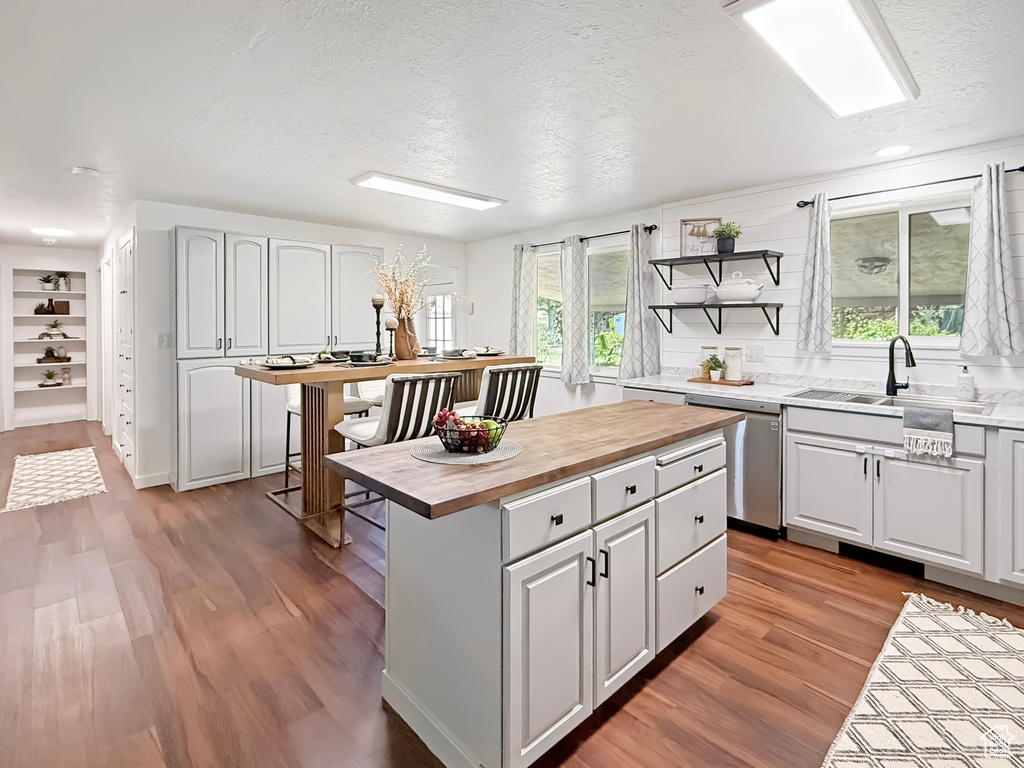 Kitchen with dishwasher, wood counters, a sink, a textured ceiling, and open shelves