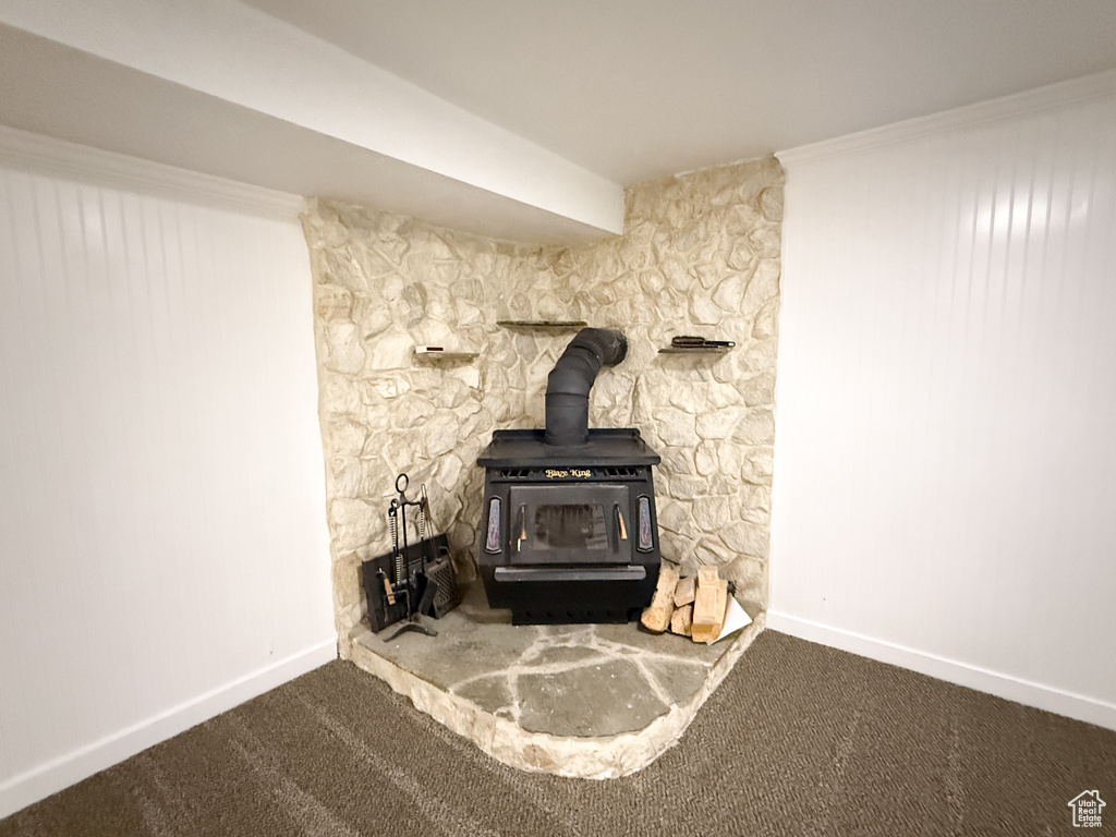 Detailed view of a wood stove, carpet floors, and baseboards