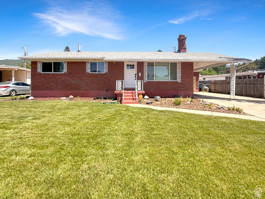 View of front of home with a chimney, brick siding, an attached carport, and driveway