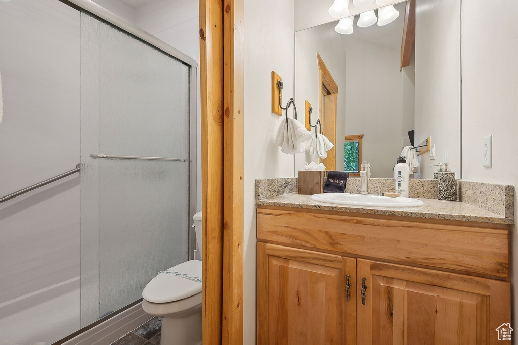 Bathroom featuring toilet, vanity, and a shower stall