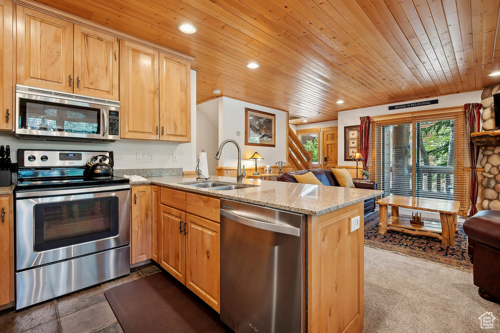 Kitchen featuring stainless steel appliances, a sink, wooden ceiling, a peninsula, and light stone counters