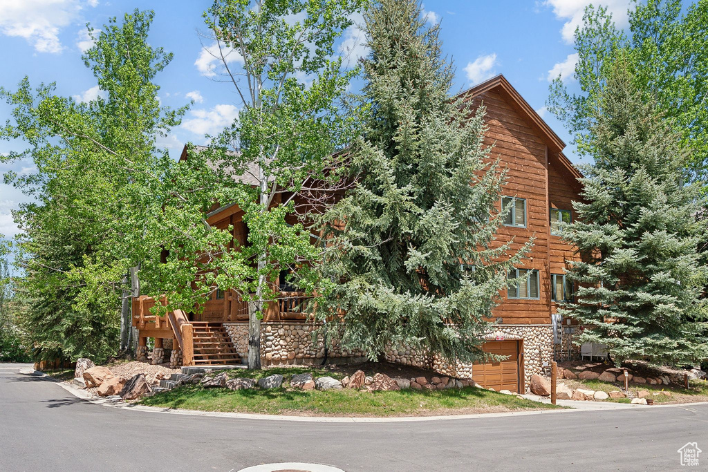 View of front of property featuring a garage, stairs, and stone siding