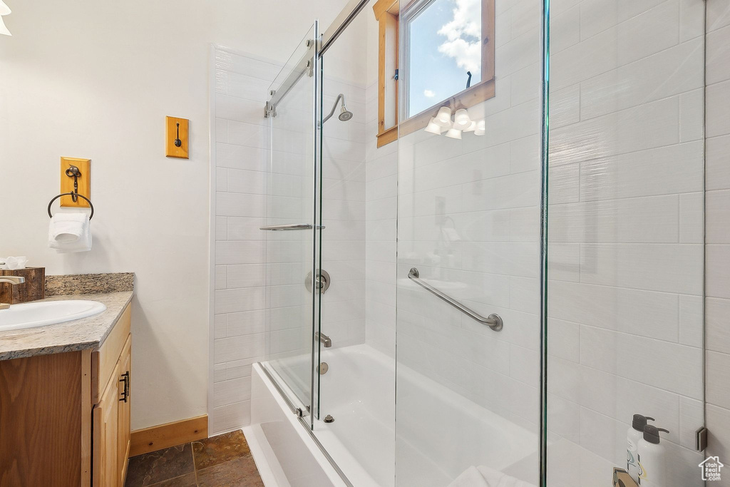 Bathroom with baseboards, vanity, and bath / shower combo with glass door