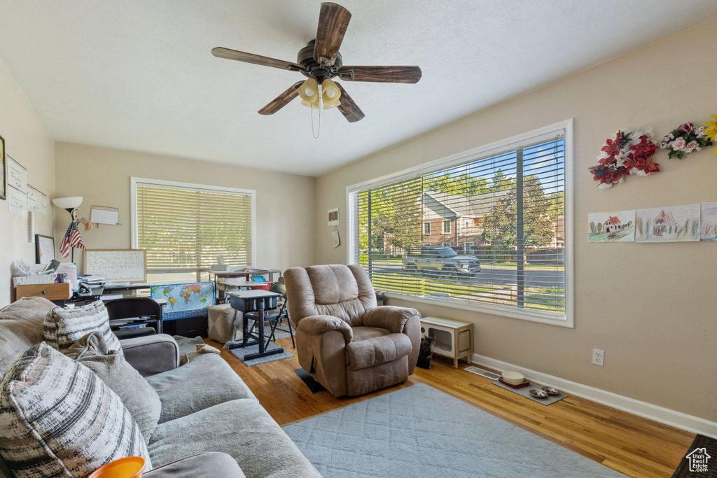 Living area with a ceiling fan, wood finished floors, and baseboards
