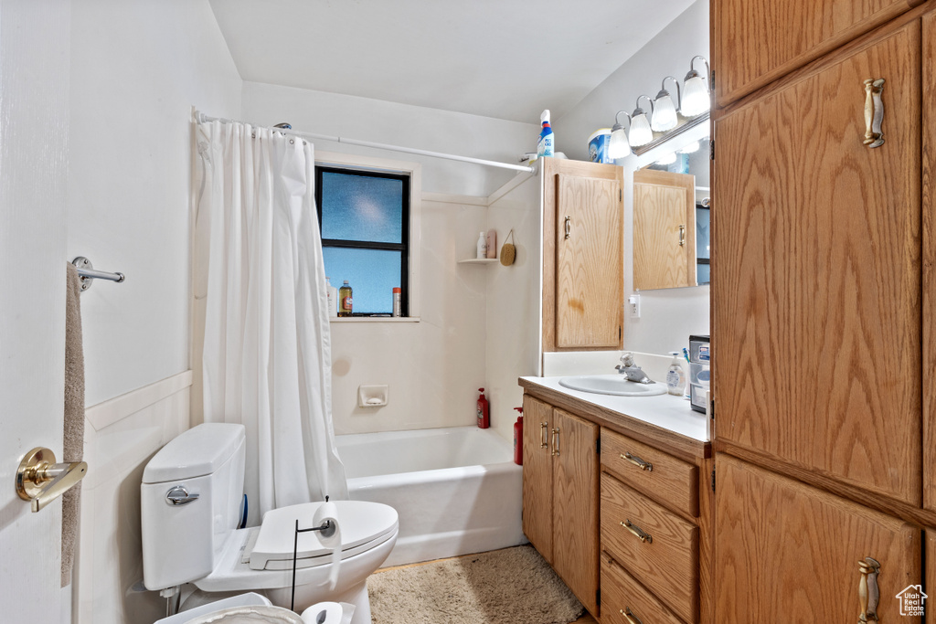 Bathroom with vanity, toilet, and shower / bathtub combination with curtain