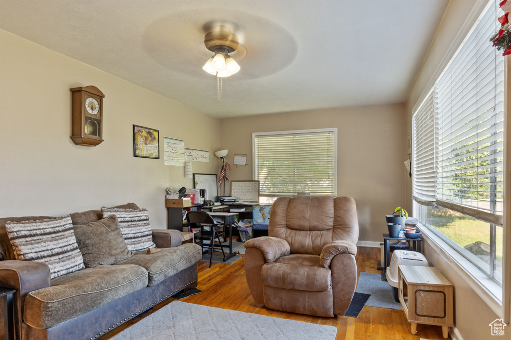 Living area with wood finished floors, plenty of natural light, and a ceiling fan