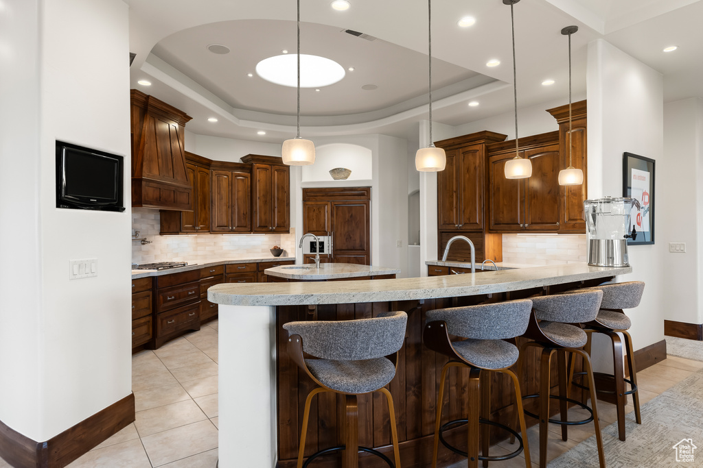 Kitchen featuring premium range hood, tasteful backsplash, a peninsula, baseboards, and recessed lighting