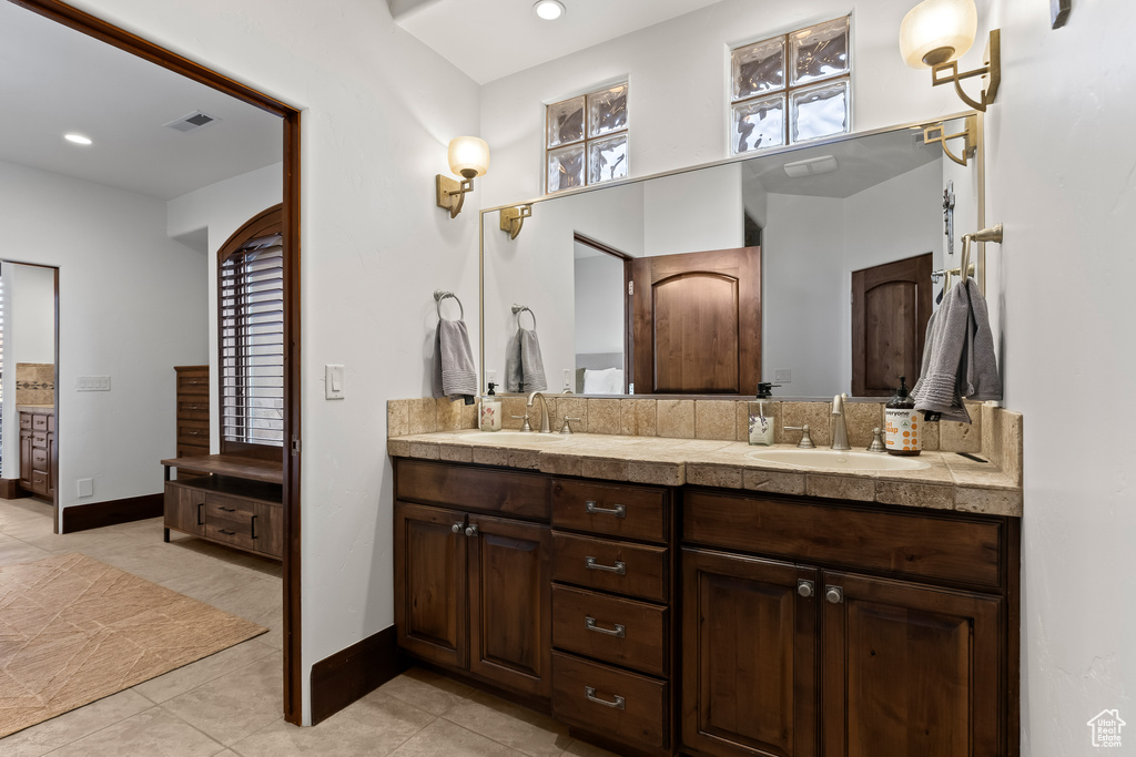 Bathroom featuring double vanity, tile patterned floors, baseboards, and recessed lighting