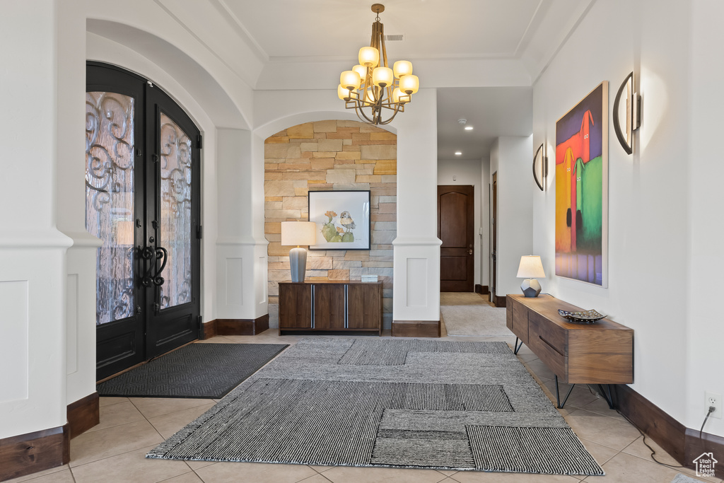 Entryway with french doors, a chandelier, ornamental molding, tile patterned floors, and baseboards