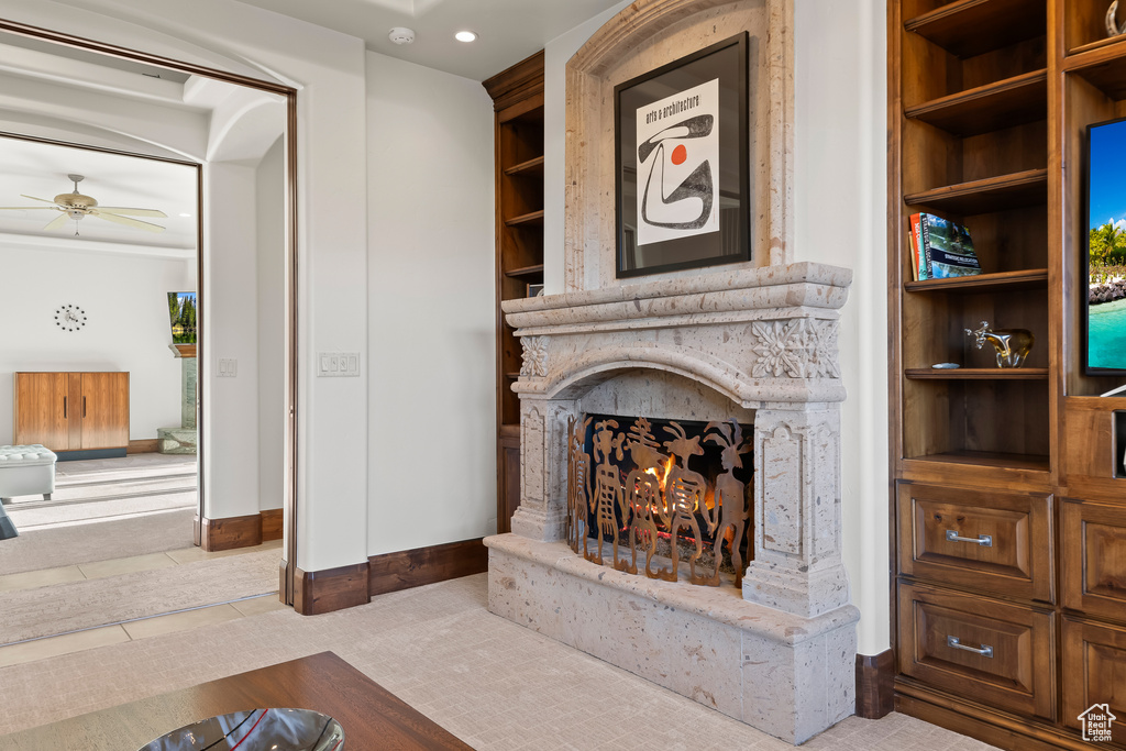 Living area with a lit fireplace, a ceiling fan, baseboards, and tile patterned flooring