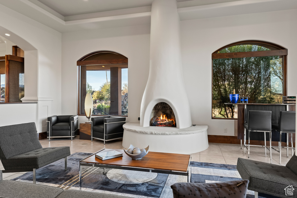 Living area featuring arched walkways, tile patterned floors, baseboards, and a large fireplace