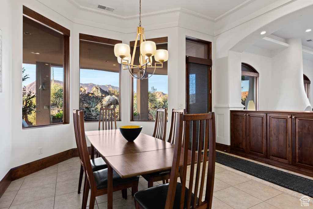 Dining space featuring light tile patterned floors, a chandelier, healthy amount of natural light, and arched walkways