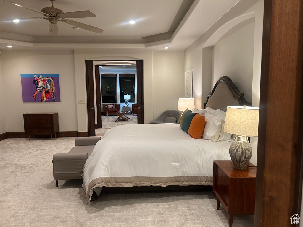 Carpeted bedroom with a raised ceiling, recessed lighting, baseboards, and a ceiling fan