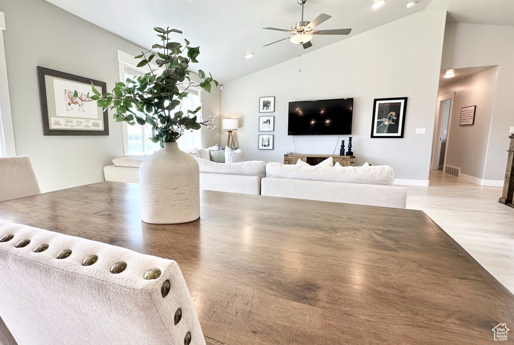Living area with ceiling fan, light wood-style flooring, and high vaulted ceiling