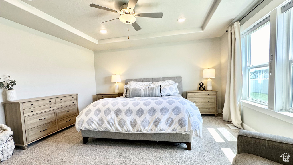 Bedroom with multiple windows, light carpet, a tray ceiling, and recessed lighting