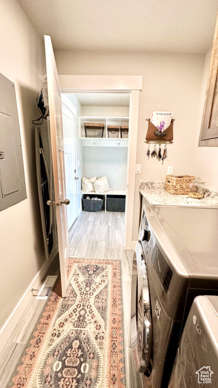 Laundry area featuring electric panel, washing machine and dryer, wood finished floors, and baseboards