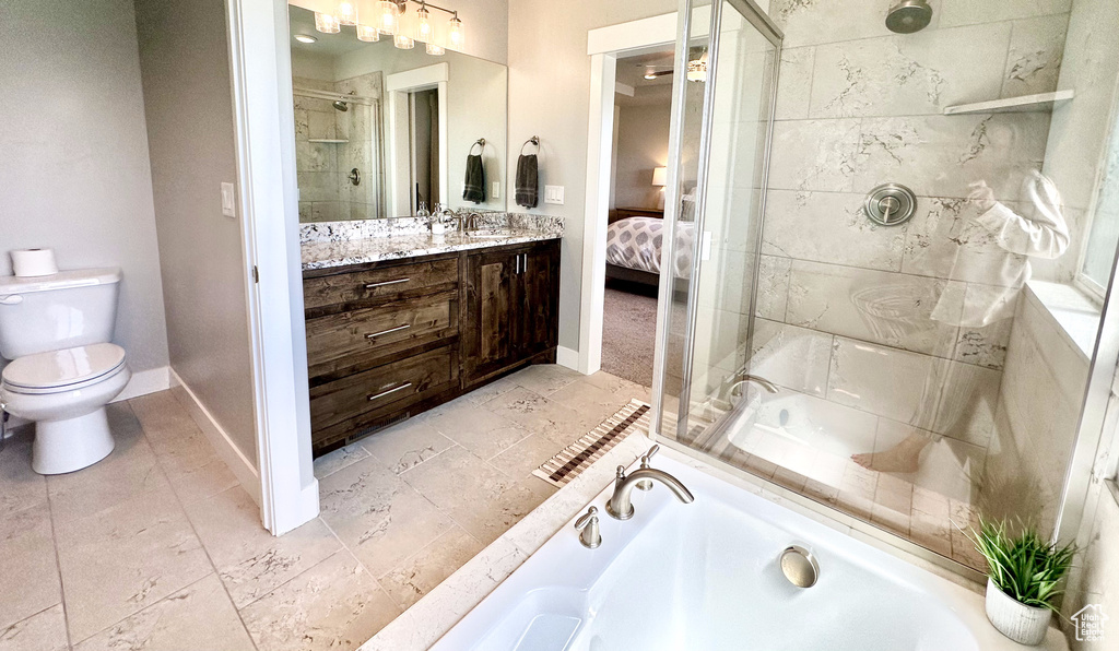 Full bath featuring vanity, a garden tub, a stall shower, toilet, and baseboards