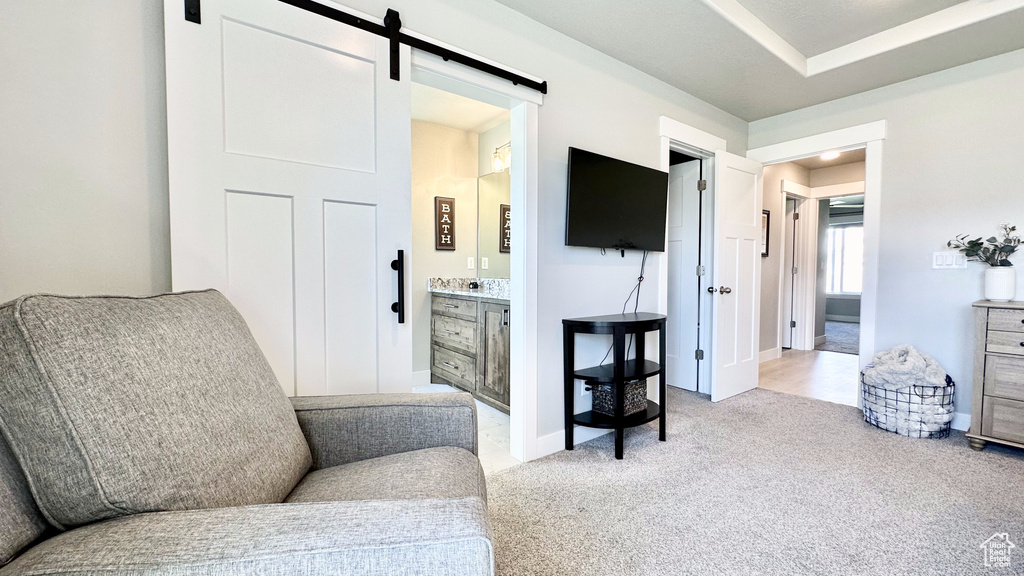 Sitting room featuring a barn door, light carpet, and baseboards