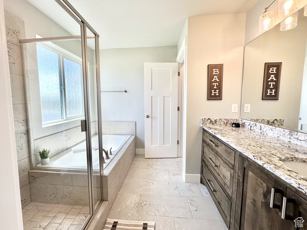 Bathroom featuring vanity, healthy amount of natural light, a garden tub, and a shower stall