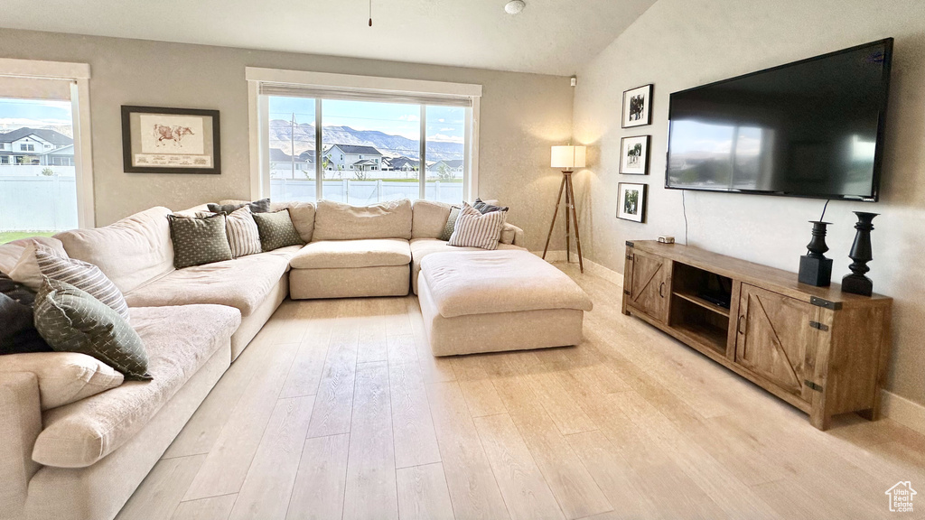 Living area with light wood-style floors and lofted ceiling