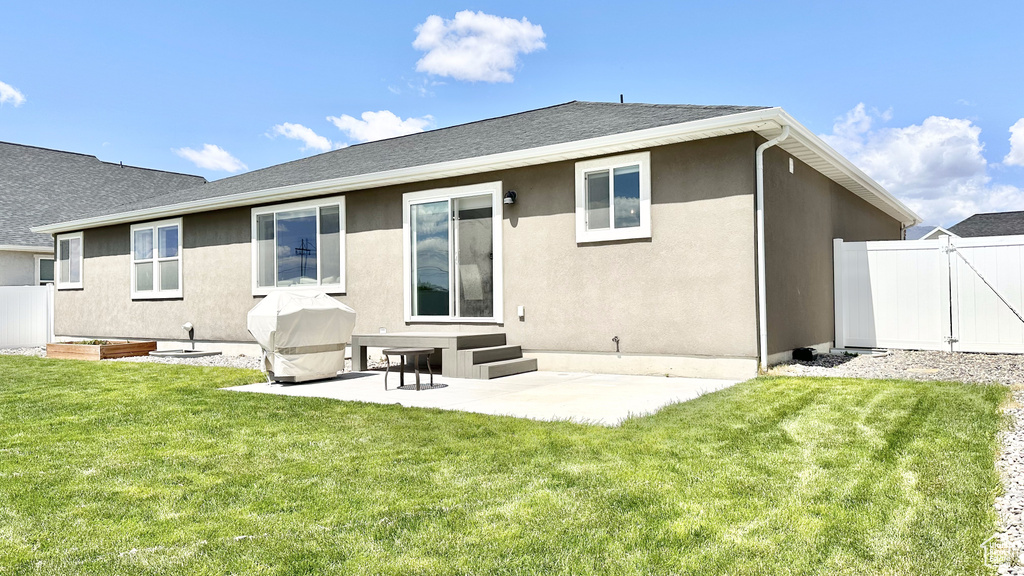 Rear view of property featuring a patio, stucco siding, a gate, entry steps, and a shingled roof