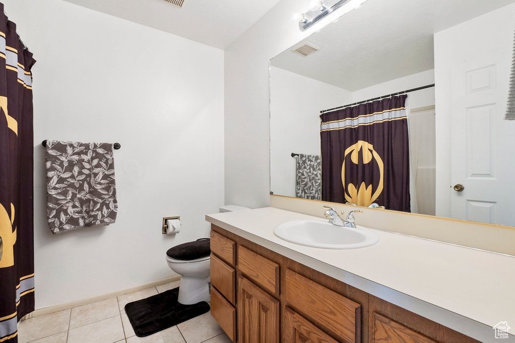 Bathroom with vanity, toilet, tile patterned floors, baseboards, and a shower with curtain